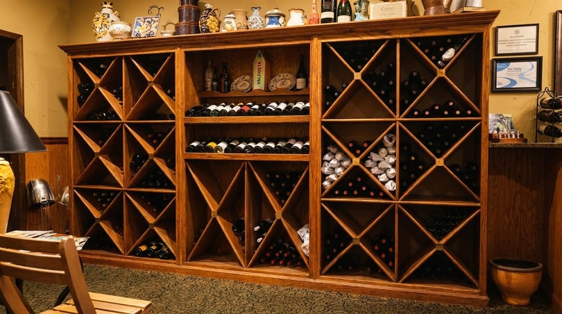 A large wooden wine rack filled with numerous bottles of wine in a restaurant setting.